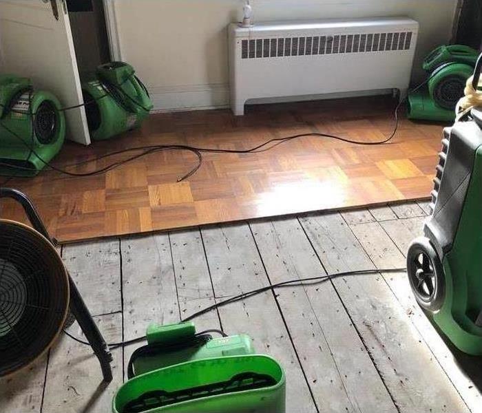 Air movers placed on a room, wooden floor removed due to water damage