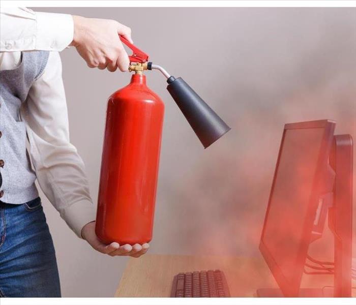 Person holding a fire extinguisher and pointing to computer