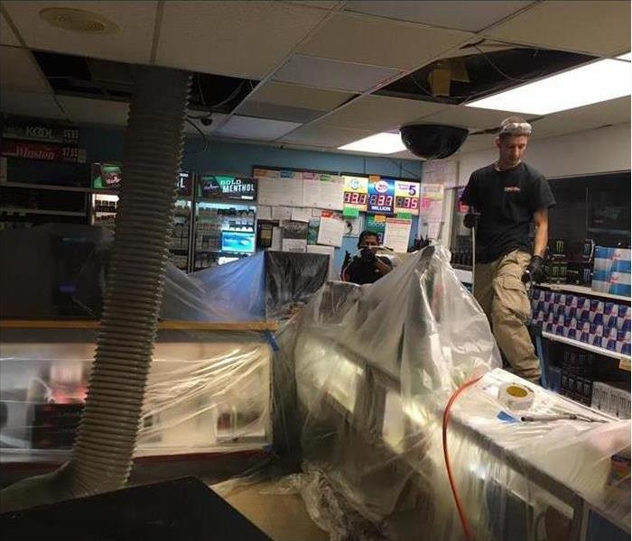 technicians covering with plastic buckets of paint inside a grocery store